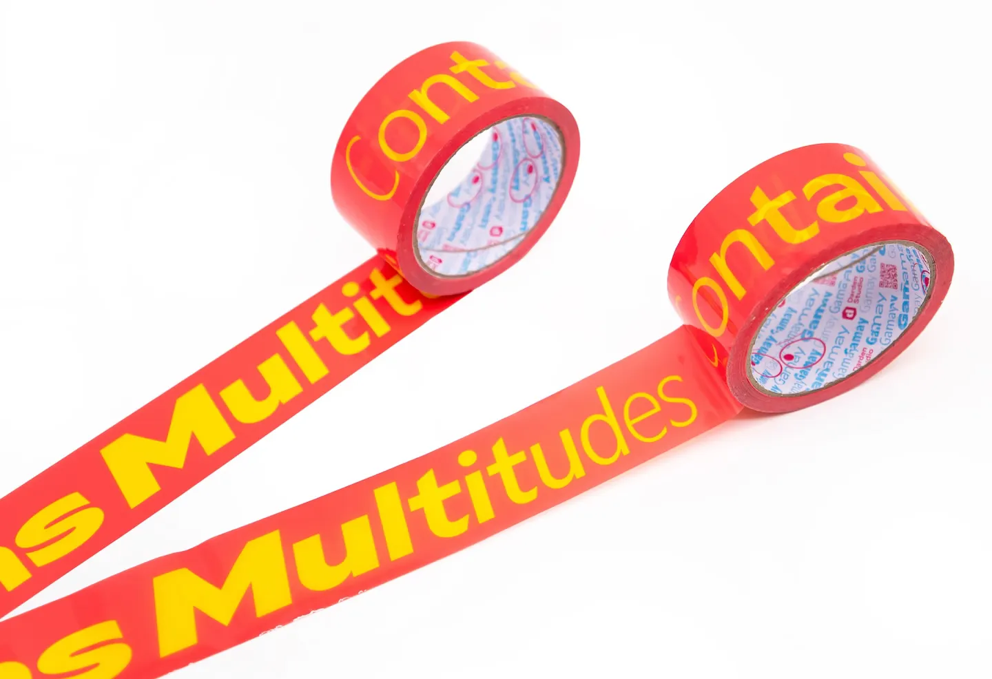 A roll of magenta packing tape with yellow letters across it reading “CONTAINS MULTITUDES”